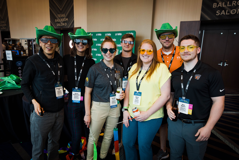 Attendees smile for a photo wearing sunglasses